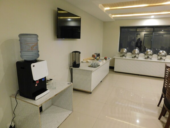 A modern kitchen with a water dispenser, coffee machine, and a blender on a counter.