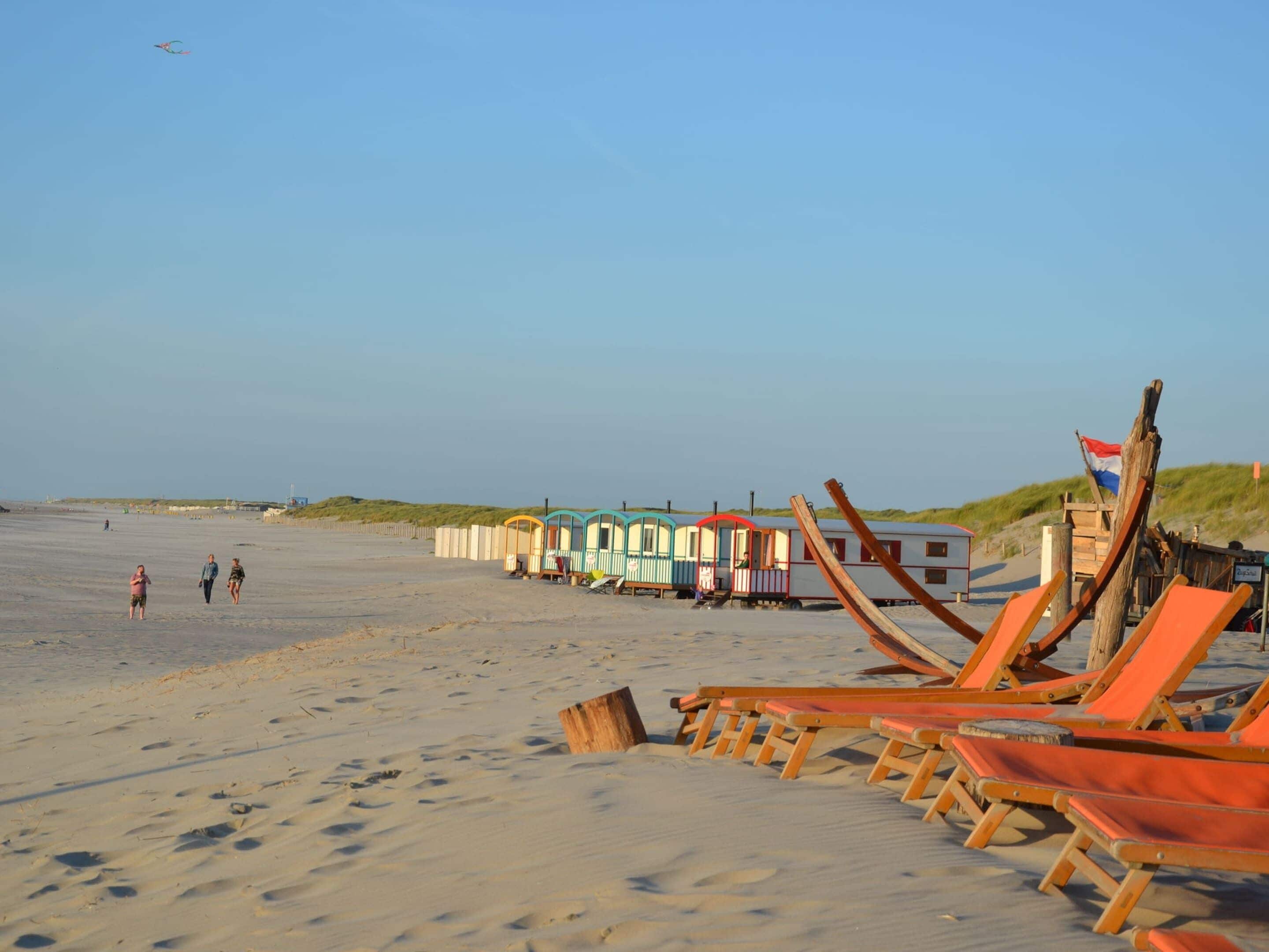 Ein Strand mit Holzliegen und bunten Strandkörben.