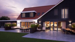 Une maison moderne avec un toit recouvert de tuiles rouges, de grandes fenêtres et des espaces aménagés à l’extérieur pour se détendre.
