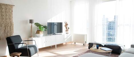 A modern living room with a sofa, a coffee table, a TV, and a plant.