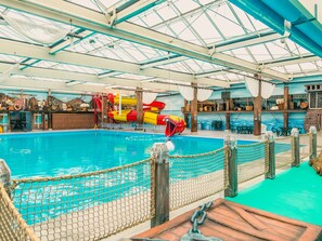 Swim and play in the large pool surrounded by a safety net, water slide, and comfortable seating areas.