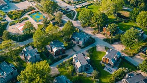 Vista aérea de um bairro residencial com casas, um parquinho e áreas verdes.