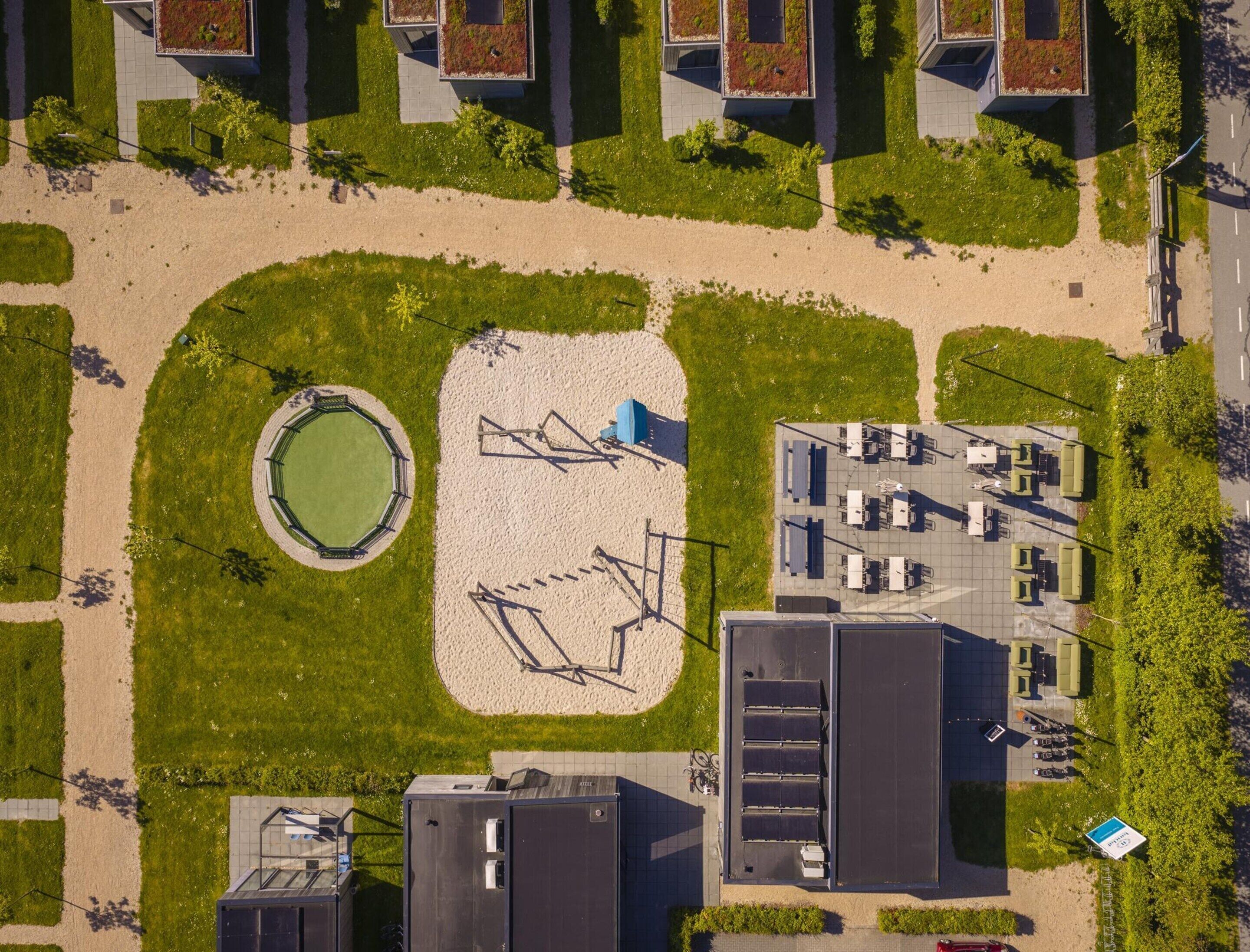 Vue aérienne d’un complexe immobilier moderne doté d’une cour intérieure, de panneaux solaires et d’un espace de stationnement.