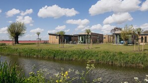 A modern building complex with a grassy area and a pond. - Lodge by Markermeer With Eco-friendly Design (Wijdenes)