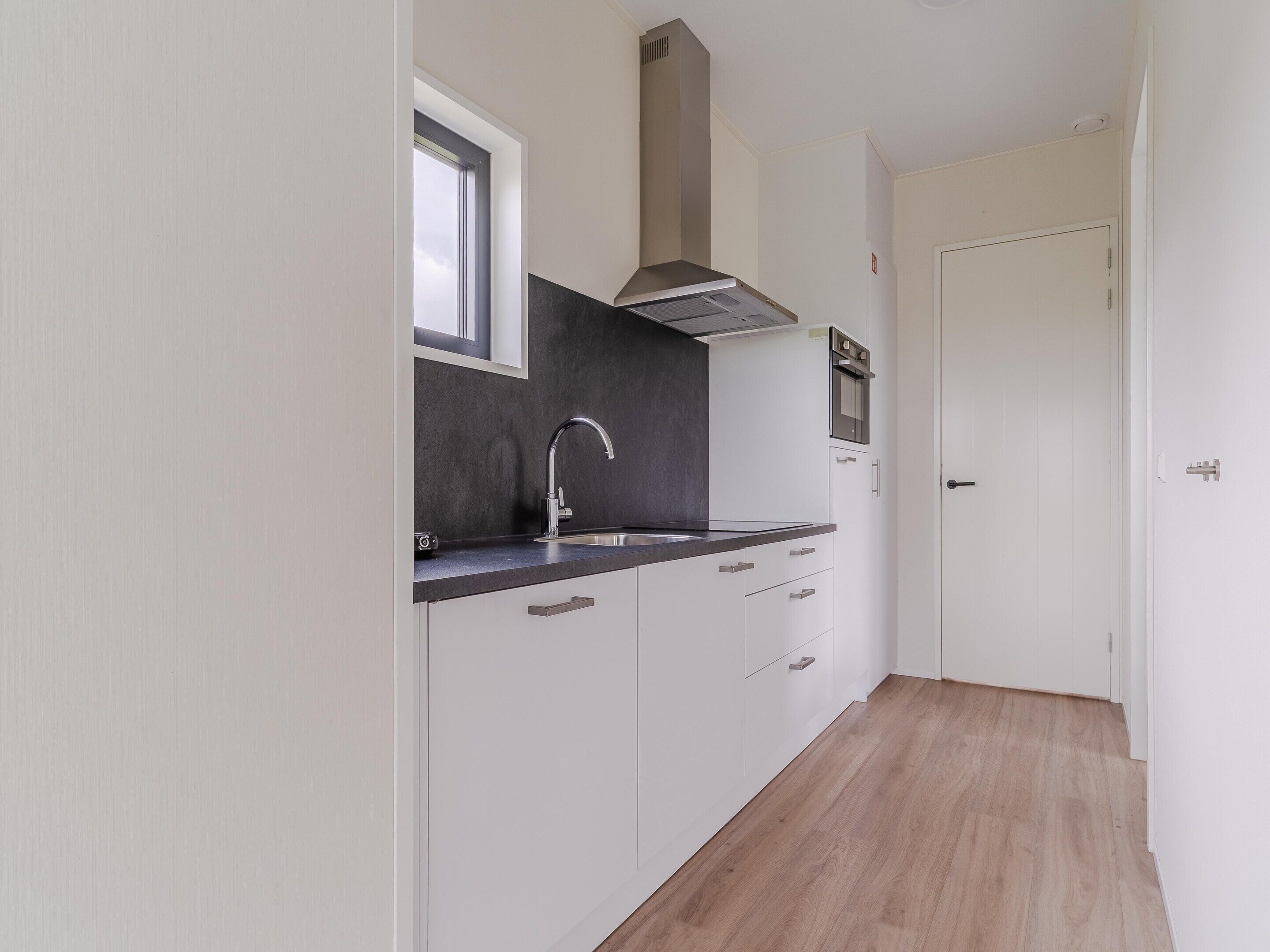 Una cocina moderna con ventana, pileta de acero inoxidable y horno empotrado.