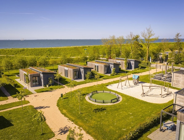 A modern resort with multiple cabins, a central circular lawn, and a view of the sea. - Lodge by Markermeer With Eco-friendly Design (Wijdenes)