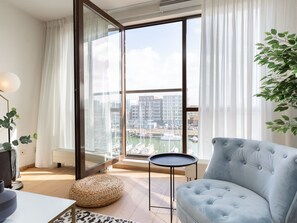A modern living room with a large sliding glass door leading to a balcony with a marina view.