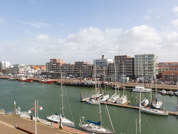 A marina with various boats docked, surrounded by buildings and a clear sky.