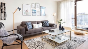 A modern living room with a grey sofa, a glass coffee table, and a black and white patterned rug. - Attractive Apartment in Den Haag with Balcony near Beach (The Hague)