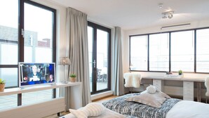 Une chambre d’hôtel moderne dotée de grandes fenêtres, d’un téléviseur à écran plat, d’un bureau et de deux lits.