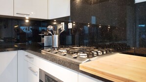 Une cuisine moderne dotée d’une hotte en acier inoxydable, d’un pare-feu noir et d’un plan de travail en bois.