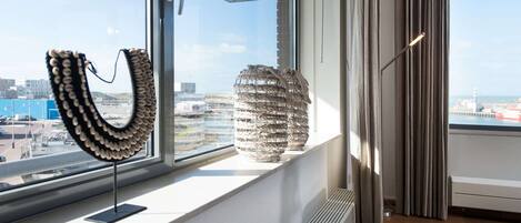 A modern room with a large window, a radiator, and two decorative items on the windowsill.