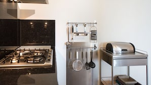 A modern kitchen with a gas stove, stainless steel appliances, and a hanging utensil rack. - Luxury Apartment in Scheveningen Harbor (The Hague)