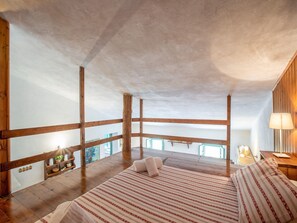 A bedroom with a wooden ceiling, a bed with striped bedding, a nightstand, and a lamp. - Apartment Near Pisa, Beaches (Collesalvetti)