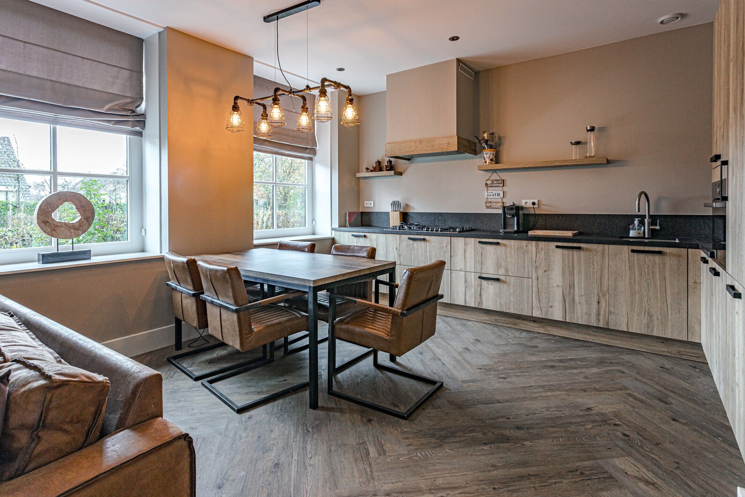 Una cocina moderna con armarios de madera, una mesa de comedor con sillas y un ventanal con persianas.