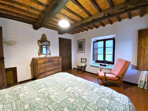 Un dormitorio con cama, cómoda, silla, ventana y ventilador de techo.