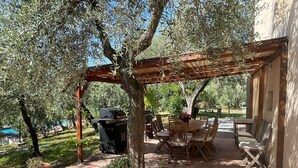An outdoor patio with a pergola, a barbecue grill, and a dining table with chairs. - Holiday Home in Toscana With Pool (Larciano)