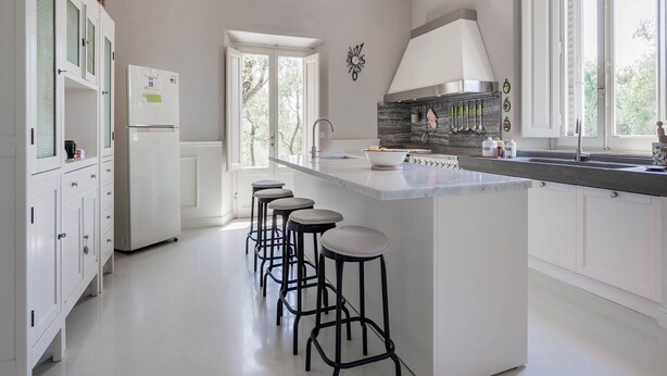 A modern kitchen with a central island, bar stools, a built-in oven, and a large window. - Holiday Home in Toscana With Pool (Larciano)