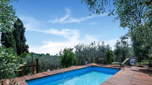 A rectangular swimming pool with a wooden deck surrounding it, set in a lush, green landscape. - Holiday Home in Toscana With Pool (Larciano)