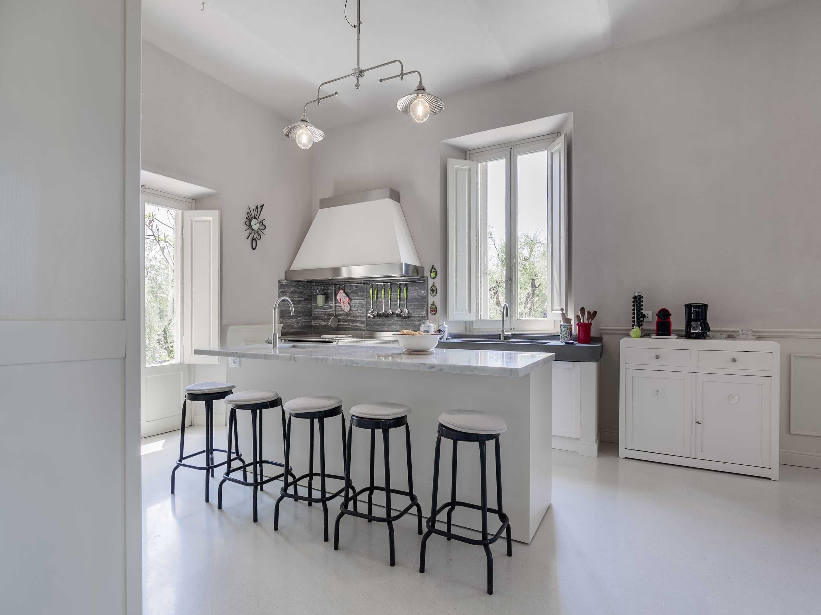 Une cuisine moderne dotée d’un îlot central, de tabourets de bar, d’une cuisinière et d’une machine à café.