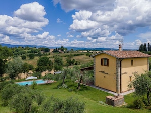 A villa with a swimming pool, surrounded by lush greenery and mountains in the background.