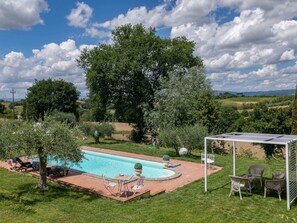 A swimming pool with lounge chairs and a pergola with seating.