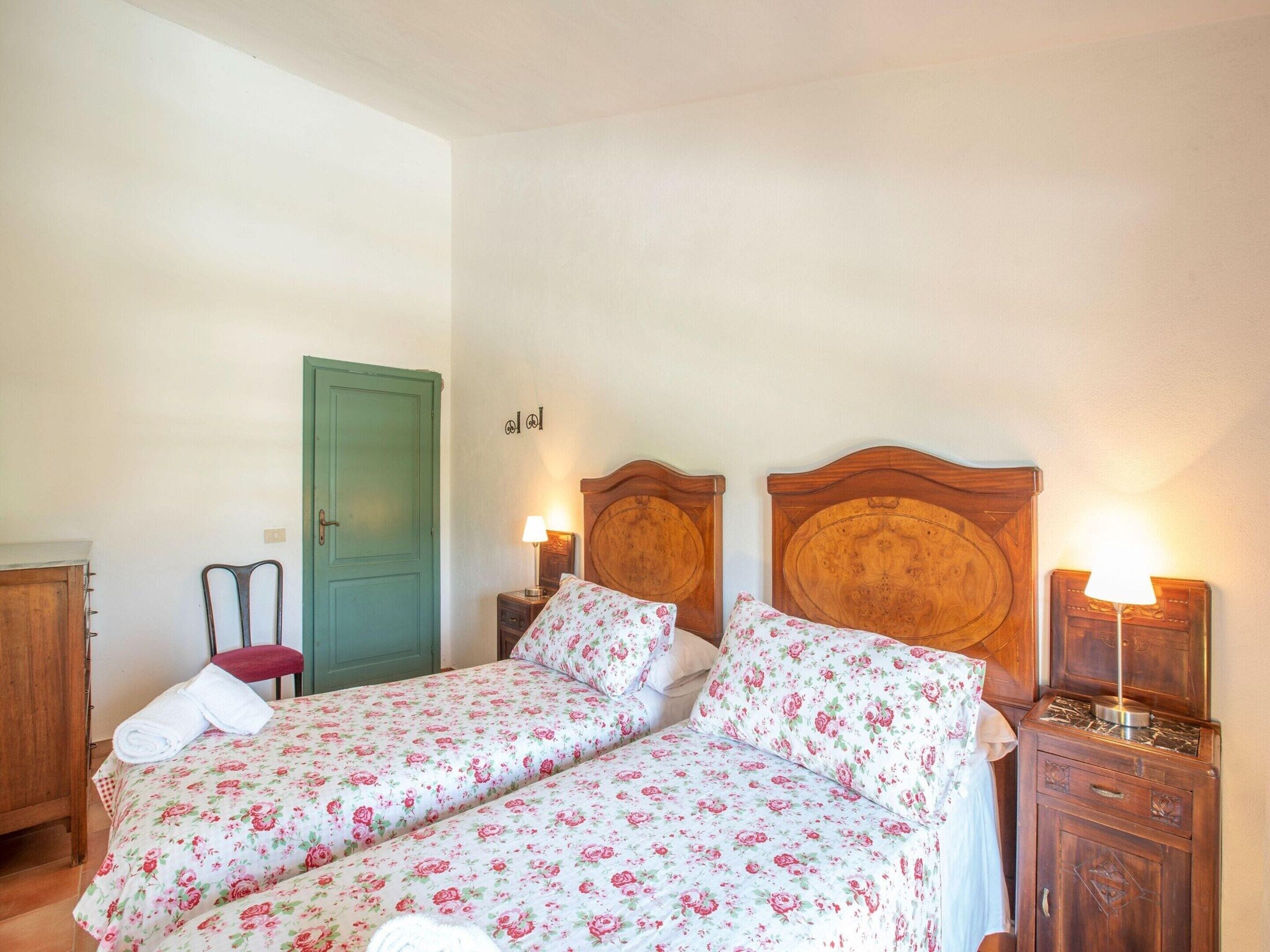 A double bed with floral bedding, a green door, and bedside lamps.