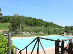 A swimming pool with lounge chairs and a wooden fence. - Apartment in Collesalvetti Near Pisa (Collesalvetti)