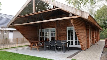 Cozy cabin with a large window offering a view of the interior, a patio area for outdoor dining, and a lawn.