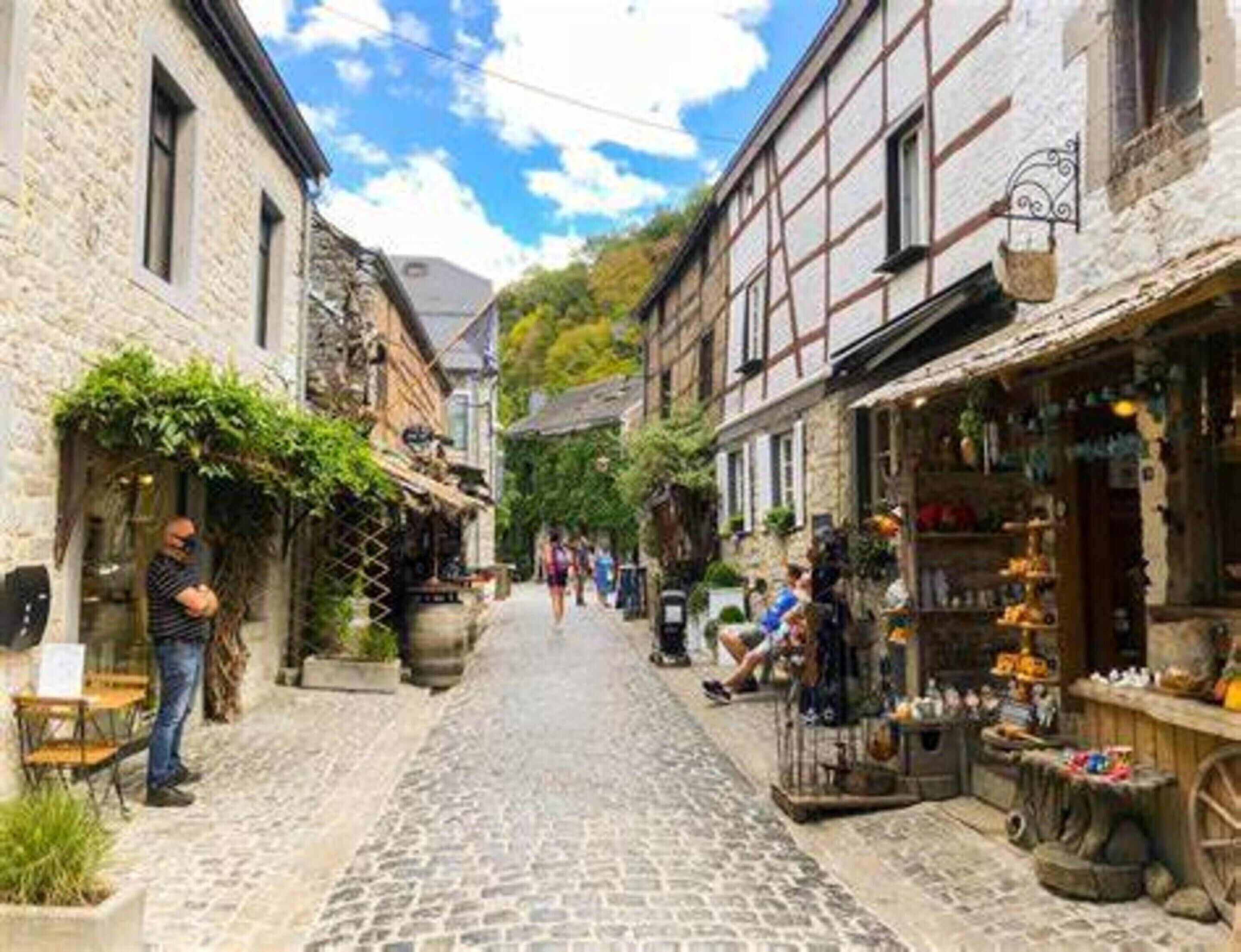 A cobblestone street lined with traditional buildings, some with shops on the ground floor.