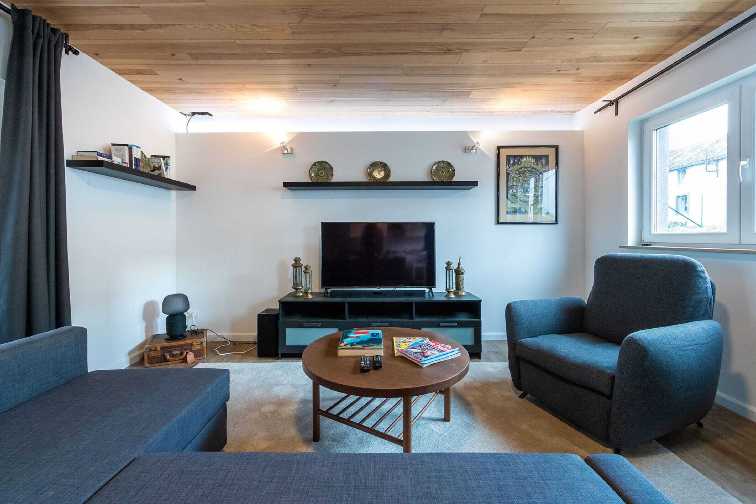Ein Wohnzimmer mit Flachbildfernseher, zwei Sofas, einem Couchtisch und einem Fenster.