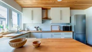 Una cocina moderna con armarios blancos, una encimera de madera y un refrigerador de acero inoxidable.