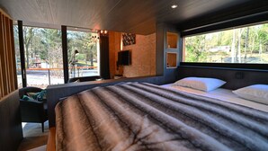 A modern bedroom with a large bed, a TV, and a view of the outdoors. - Ecological Holiday Home near Durbuy with Nordic Bath (Durbuy)