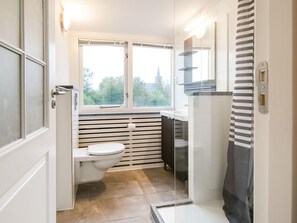 Ein kleines Badezimmer mit Toilette, Fenster und Duschbereich.