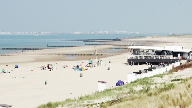 A beach with a lifeguard tower, sandy beach, and a view of the sea and distant city skyline. - Modern Holiday Home in Groede With a Terrace (Groede)