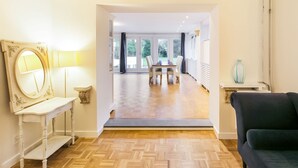 A spacious room with a wooden herringbone floor, a dining area with a table and chairs, and a large mirror on the left. - Modern Holiday Home in Groede With a Terrace (Groede)