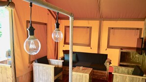 Een landelijk interieur met een houten tafel, stoelen, een bank en hangende lampen.