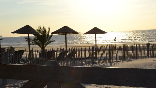 Een strand met houten parasols en een houten omheining.