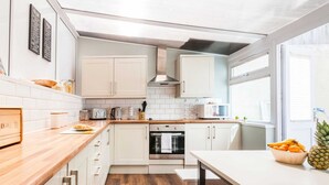 Una cocina moderna con armarios blancos, encimera de madera y una mesa de comedor.