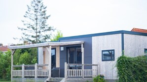 A modern single-story building with a covered porch, large windows, and a wooden fence.