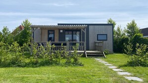 A modern wooden house with a porch, large windows, and a small deck.