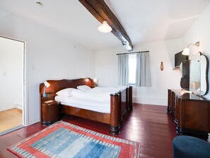Een slaapkamer met een houten bed, nachtkastje, dressoir en een spiegel.