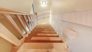 Un escalier avec des marches en bois et une rampe en bois, qui monte.