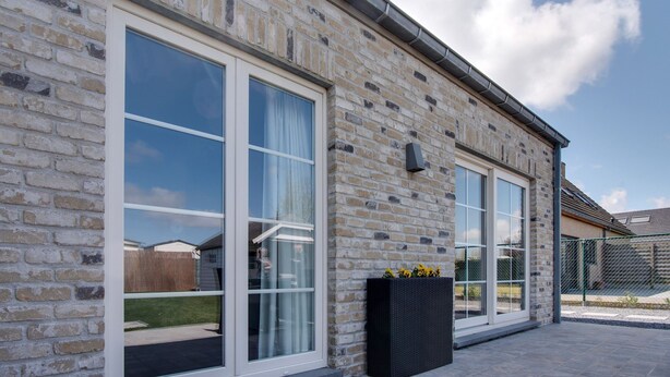 A brick building with large windows and a black planter with flowers. - Modern Holiday Home in De Haan With Garden (De Haan)