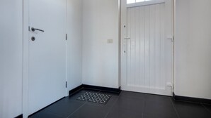 A hallway with a white door on the left and a white door with a window on the right. - Modern Holiday Home in De Haan With Garden (De Haan)