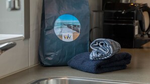 Cocina con cafetera, una toalla y una bolsa con un adhesivo de escena de playa.