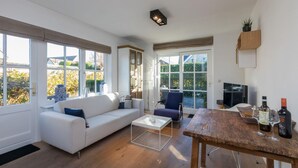 A modern living room with a sofa, coffee table, and dining table. - Attractive Apartment near Center & Beach (Zoutelande)