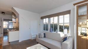 A modern living room with a sofa, a coffee table, and a large window. - Attractive Apartment near Center & Beach (Zoutelande)
