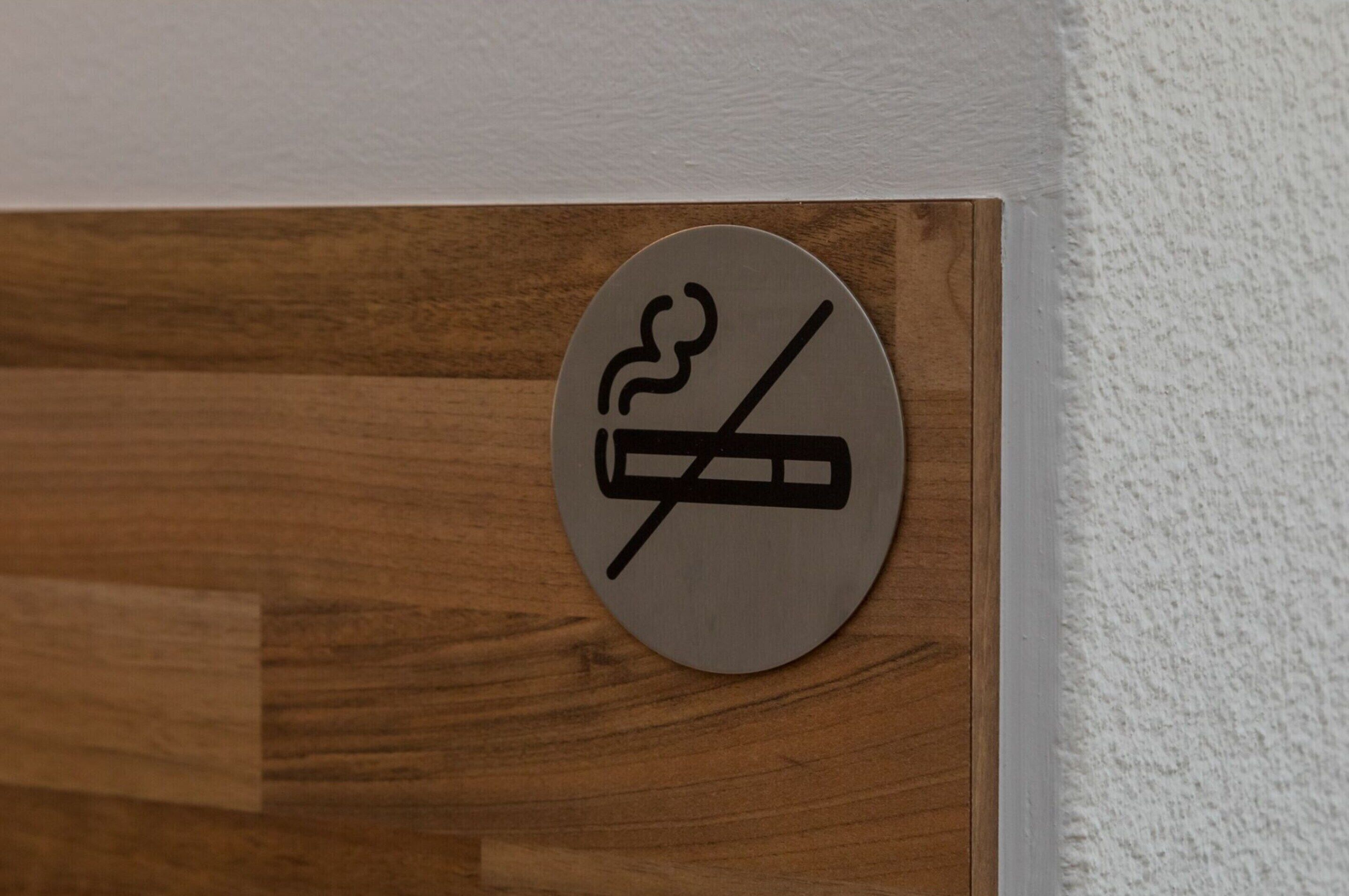 Un letrero circular que indica prohibido fumar, sobre un panel de madera.