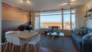 A modern living room with a dining area, large windows with a view, and a balcony. - Romantic Coastal Retreat With Scenic Balcony (Zoutelande)